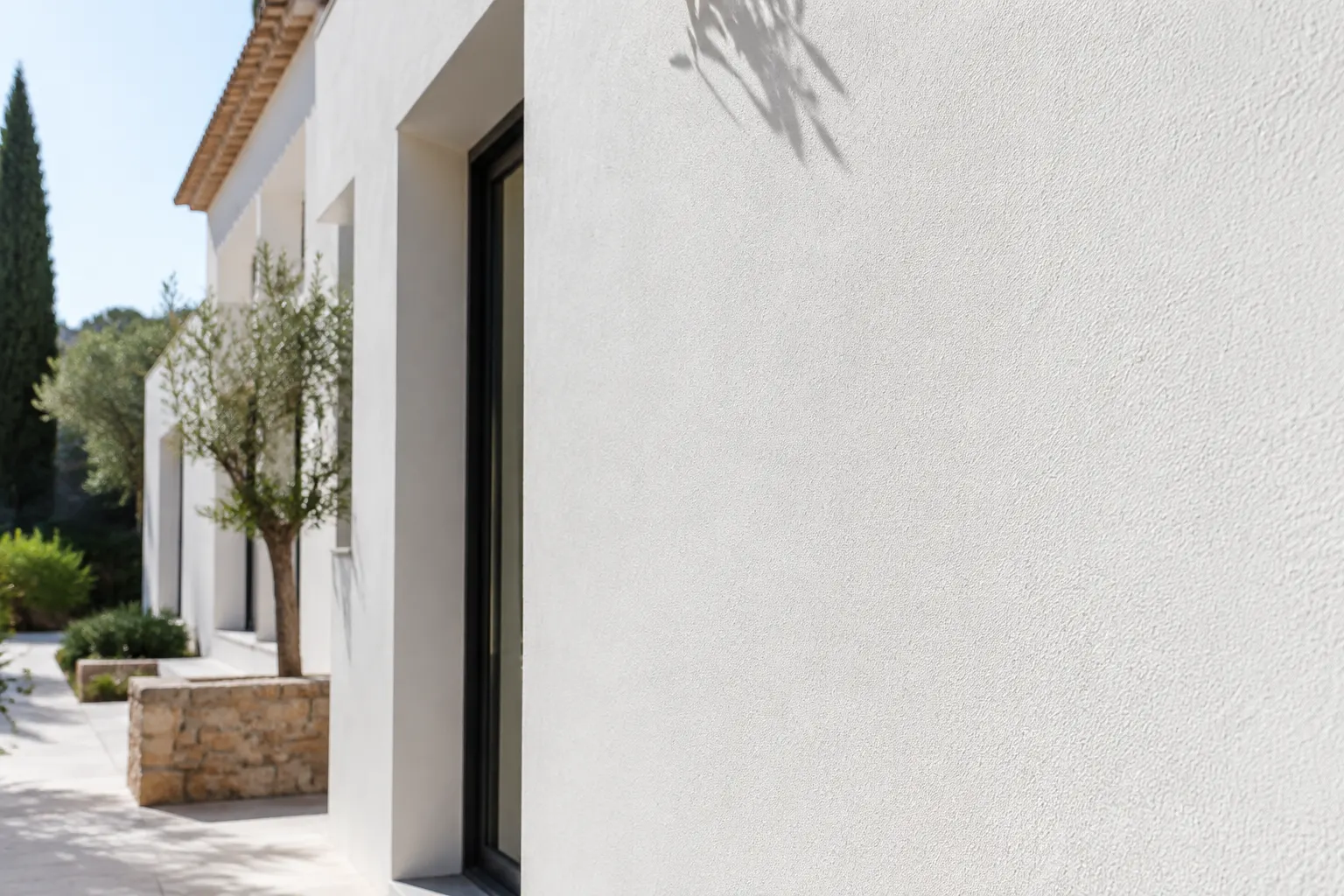 Fachada mediterr&aacute;nea blanca con revestimiento rugoso de grano fino y textura exterior suave.
